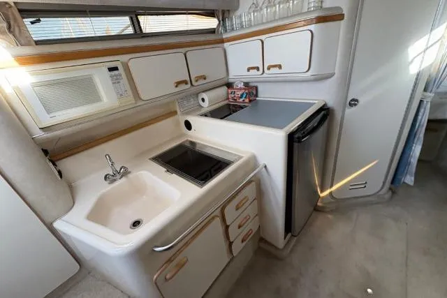 Slide: The Image of 1993 Sea Ray Sundancer 330 yacht kitchen with sink, stove, microwave, and fridge. - 98