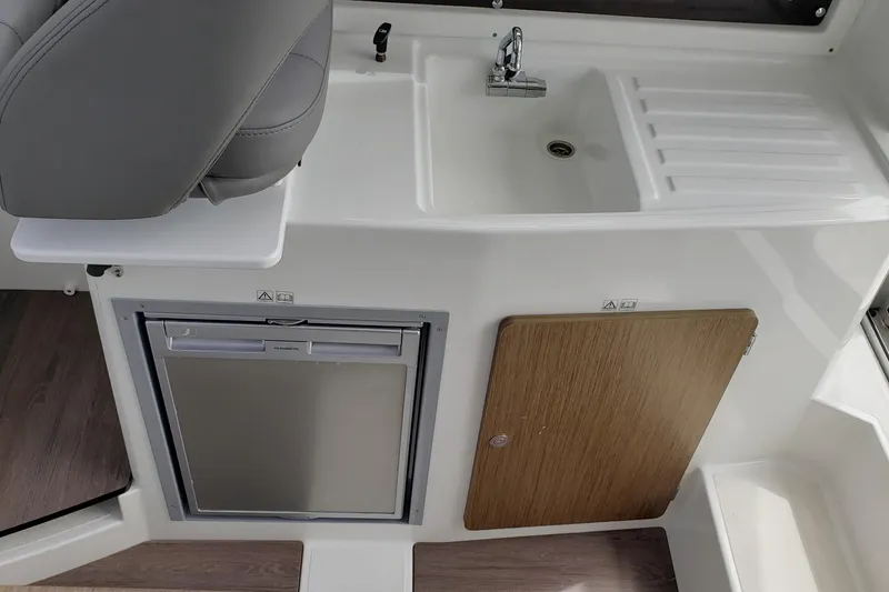 Slide: The Image of Interior of 2019 Beneteau Antares 23 featuring sink, fridge, and storage cabinet. - 18