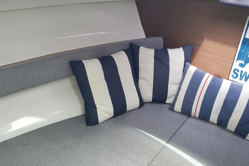 Slide: The Image of Interior of 2019 Beneteau Antares 23 with striped cushions on a gray sofa. - 30