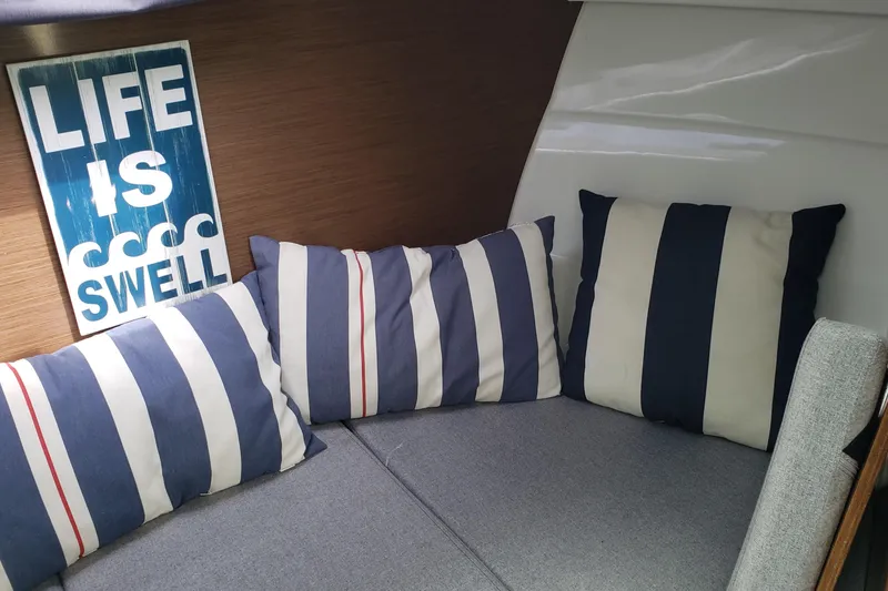 Slide: The Image of Cozy interior of 2019 Beneteau Antares 23 with striped cushions and "Life is Swell" sign. - 31