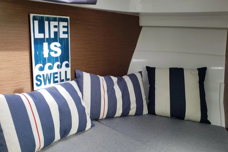 Slide: The Image of Cozy interior of 2019 Beneteau Antares 23 with striped pillows and "Life is Swell" sign. - 35