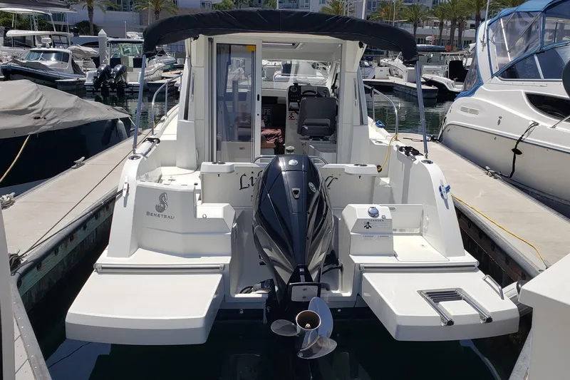 Slide: The Image of 2019 Beneteau Antares 23 docked, showcasing rear view and outboard motor. - 46