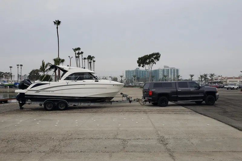 Slide: The Image of 2019 Beneteau Antares 23 boat on trailer, towed by a black truck in a marina. - 55