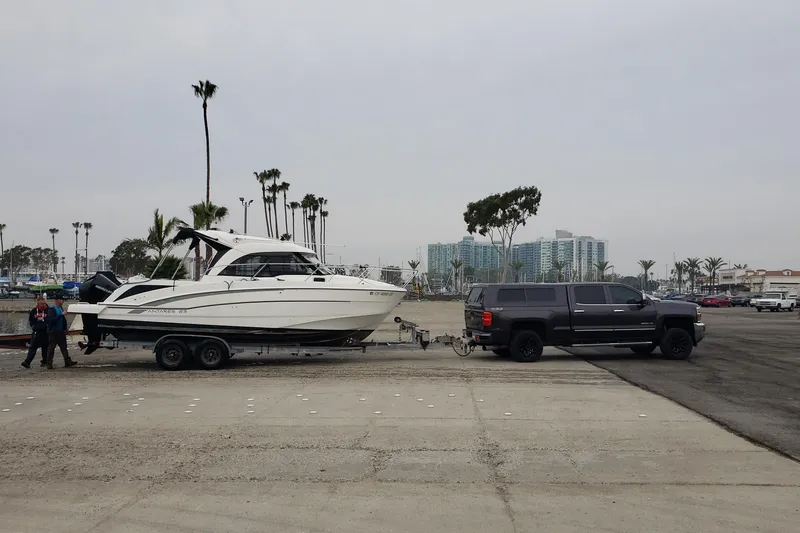 Slide: The Image of 2019 Beneteau Antares 23 boat on trailer, towed by a black truck near marina. - 56