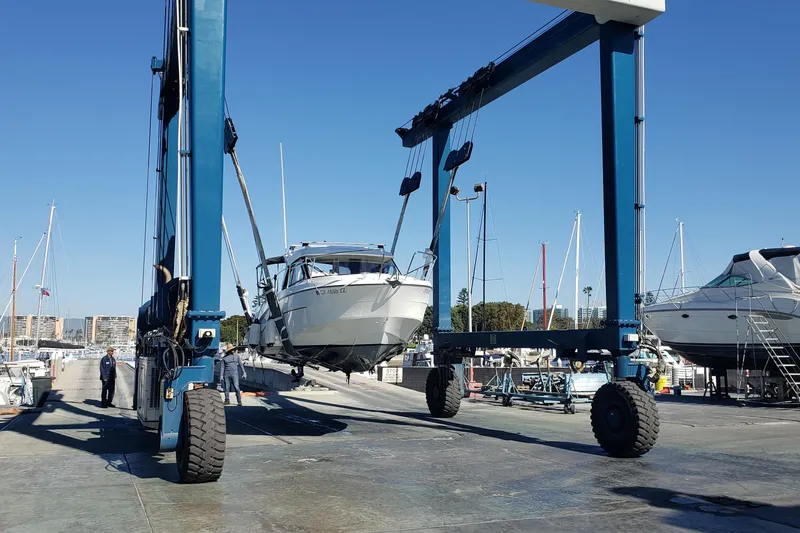 Slide: The Image of 2019 Beneteau Antares 23 being lifted by a boat hoist at a marina. - 59