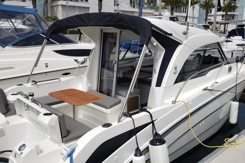 Slide: The Image of 2019 Beneteau Antares 23 docked, featuring a sleek design and outdoor seating area. - 7