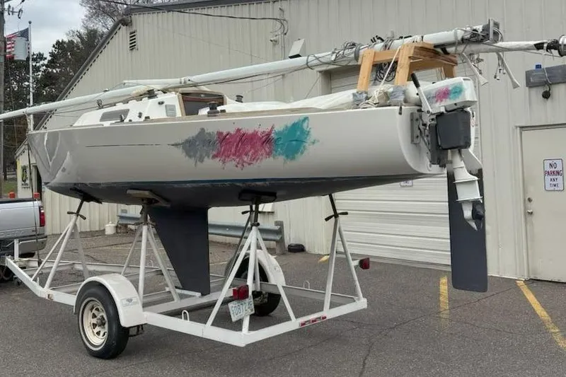 Slide: The Image of 1988 J Boats J/22 sailboat on trailer, colorful hull design, parked outside a building. - 10