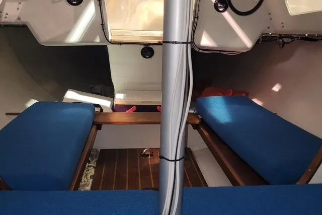 Slide: The Image of Interior of a 1988 J Boats J/22 sailboat with blue seating and wooden flooring. - 6