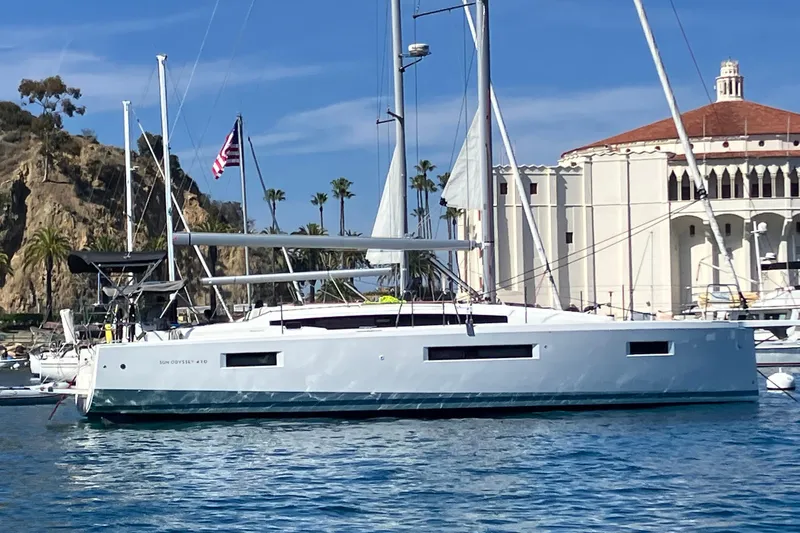 The Image of 2024 Jeanneau Sun Odyssey 410 sailboat docked near scenic coastal architecture. - 0