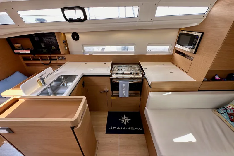 Slide: The Image of Interior of 2024 Jeanneau Sun Odyssey 410 yacht, featuring modern kitchen and seating area. - 74
