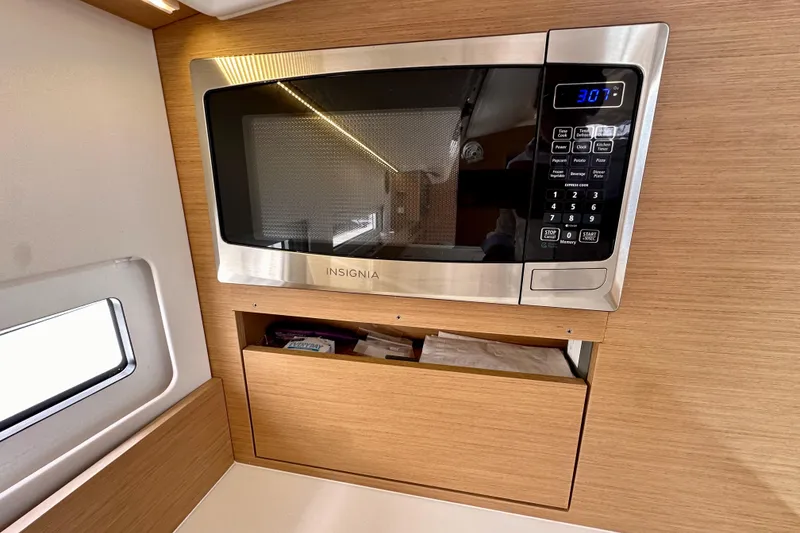 Slide: The Image of Microwave in 2024 Jeanneau Sun Odyssey 410 yacht kitchen, featuring modern wood cabinetry. - 82