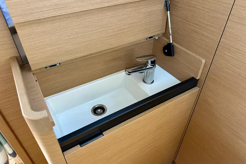 Slide: The Image of 2024 Jeanneau Sun Odyssey 410 interior sink with modern faucet and wooden cabinetry. - 88