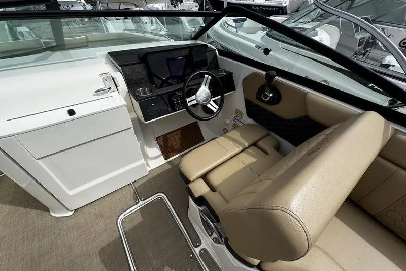 Slide: The Image of 2019 Sea Ray SDX 250 boat interior with steering wheel and beige seating. - 14