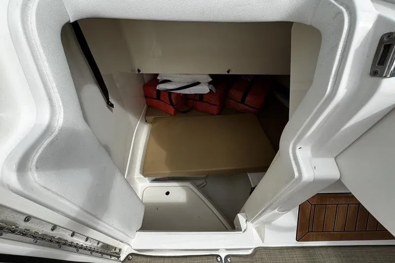 Slide: The Image of 2019 Sea Ray SDX 250 storage compartment with life jackets and seating area. - 17