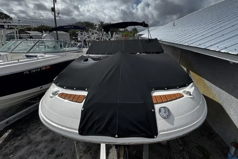 Slide: The Image of 2019 Sea Ray SDX 250 boat with black cover, docked beside other boats. - 3