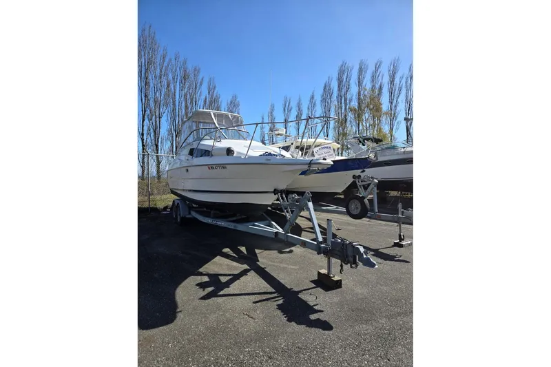Slide: The Image of 1998 Bayliner 2655 Ciera Sunbridge boat on trailer, parked outdoors under clear blue sky. - 2