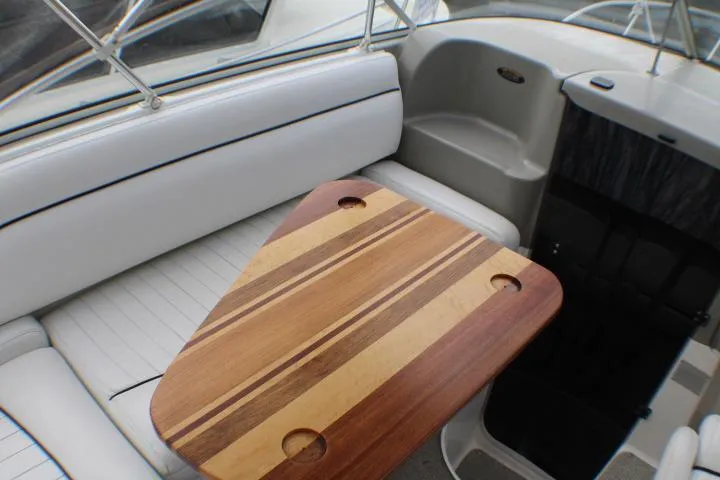 Slide: The Image of 1998 Bayliner 2655 Ciera Sunbridge interior with striped wooden table and white seating. - 27