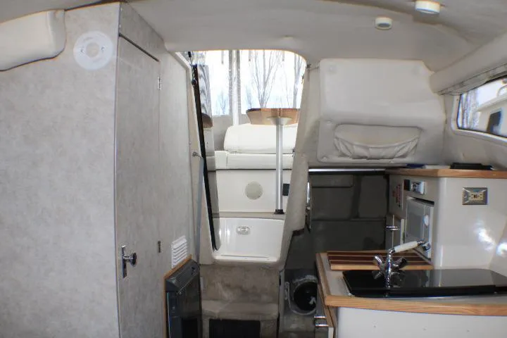 Slide: The Image of Interior of a 1998 Bayliner 2655 Ciera Sunbridge boat, featuring a compact kitchen area. - 50