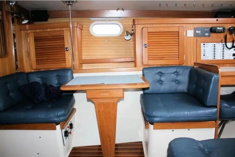 Slide: The Image of Interior of 2001 Catalina 36 MkII sailboat with blue cushioned seating and wooden cabinetry. - 2