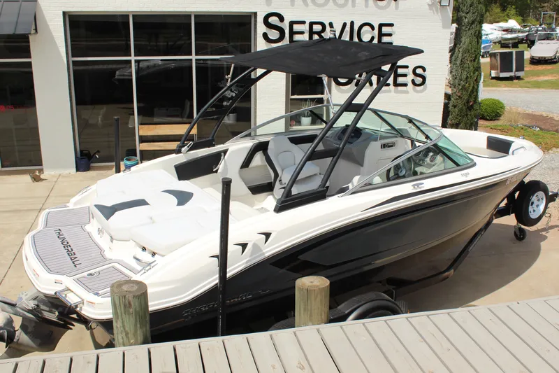 Slide: The Image of 2016 Chaparral 21 H2O Sport boat with black canopy, docked near service center. - 2