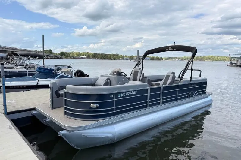 The Image of 2018 Veranda VR25RC pontoon boat docked on a calm lake under a cloudy sky. - 0