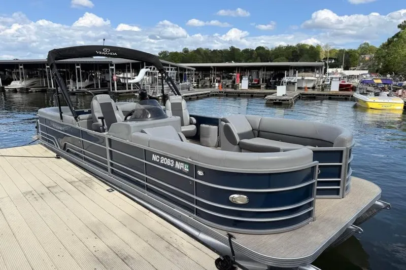 Slide: The Image of 2018 Veranda VR25RC pontoon boat docked at a marina under a clear blue sky. - 2