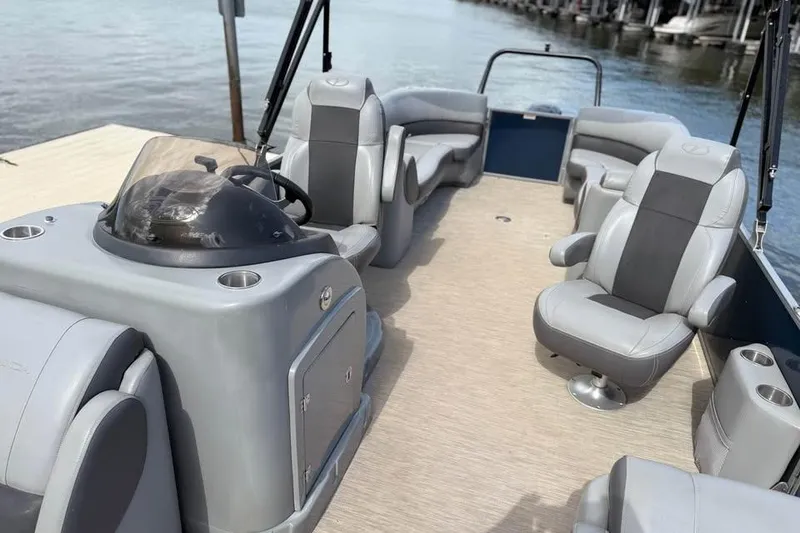 Slide: The Image of 2018 Veranda VR25RC pontoon boat interior with gray seating and helm, docked by water. - 7