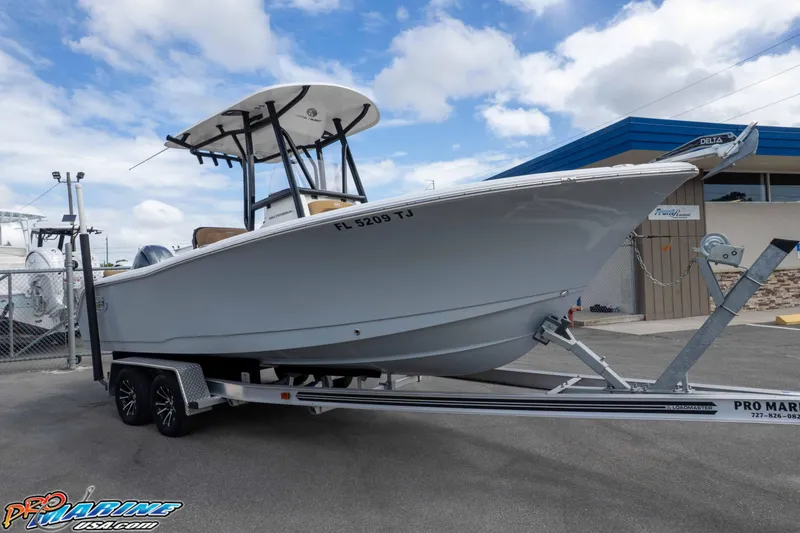 Slide: The Image of 2023 Sea Hunt Ultra 229 boat on trailer, parked outdoors under a cloudy sky. - 12