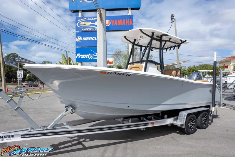 Slide: The Image of 2023 Sea Hunt Ultra 229 boat on trailer at dealership, clear sky background. - 16