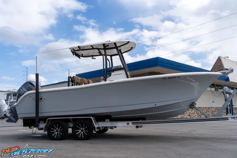 Slide: The Image of 2023 Sea Hunt Ultra 229 boat on trailer, parked outdoors under a blue sky. - 19