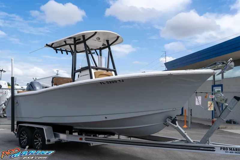 Slide: The Image of 2023 Sea Hunt Ultra 229 boat on trailer, displayed outdoors under blue sky. - 21