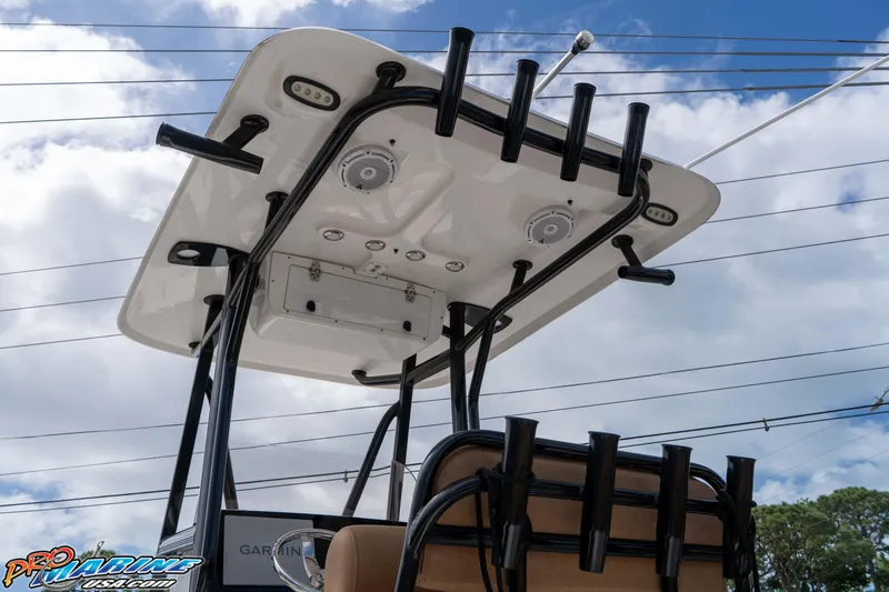 Slide: The Image of 2023 Sea Hunt Ultra 229 T-top with rod holders and speakers under a cloudy sky. - 27