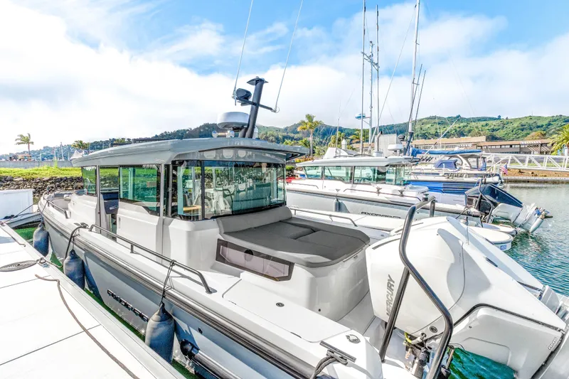 Slide: The Image of 2021 Axopar 37 XC Cross Cabin boat docked in a scenic marina. - 3