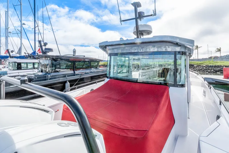 Slide: The Image of 2021 Axopar 37 XC Cross Cabin boat docked with red cover, clear sky background. - 43