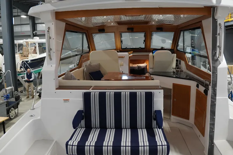 Slide: The Image of 2024 True North 34 yacht interior with striped seating and wooden accents in a showroom. - 23