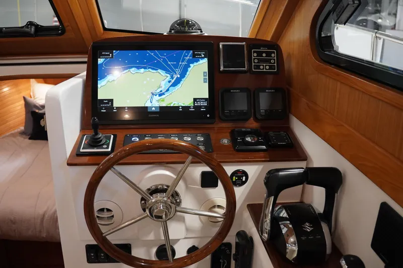 Slide: The Image of 2024 True North 34 boat helm with navigation screen and wooden steering wheel. - 32
