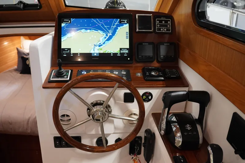 Slide: The Image of 2024 True North 34 boat helm with navigation display, wooden steering wheel, and control panel. - 33