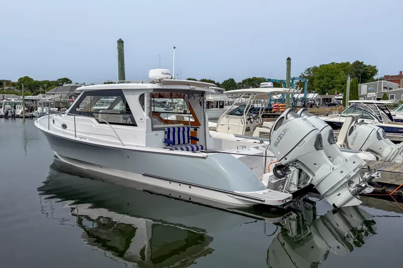 Slide: The Image of 2024 True North 34 boat docked with Suzuki outboard engines, in a marina setting. - 40