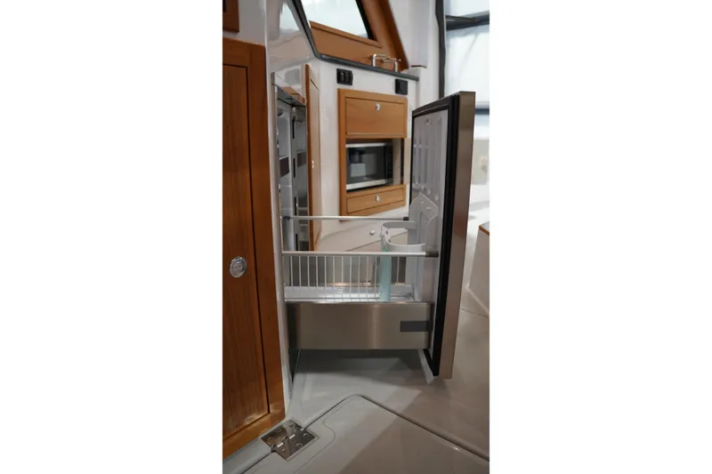 Slide: The Image of 2024 True North 34 yacht interior with open refrigerator and wooden cabinetry. - 5