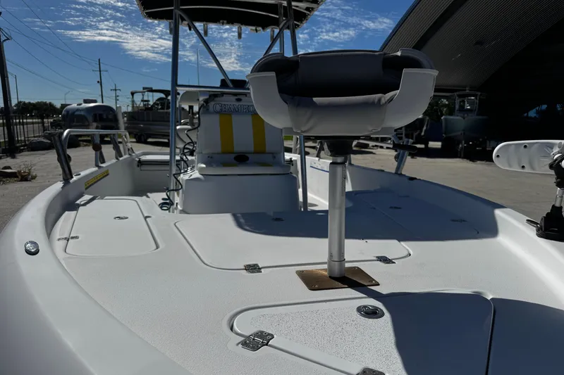Slide: The Image of 2006 Champion 24 Bay Champ boat deck with seating and console under a clear sky. - 10