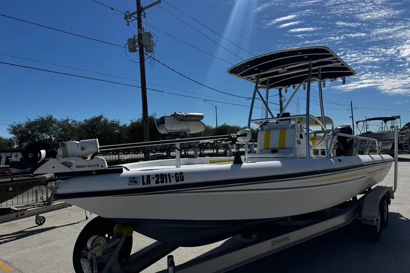 Slide: The Image of 2006 Champion 24 Bay Champ boat on trailer under clear blue sky. - 4