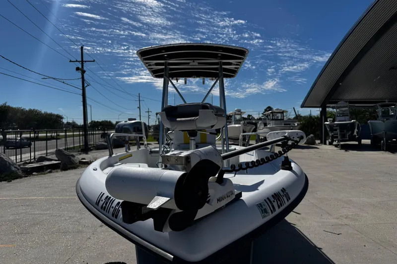 Slide: The Image of 2006 Champion 24 Bay Champ boat with trolling motor, parked outdoors under a clear blue sky. - 7