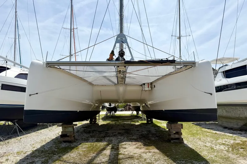 Slide: The Image of 2016 Outremer 45 catamaran on land, surrounded by other boats, under a clear sky. - 100