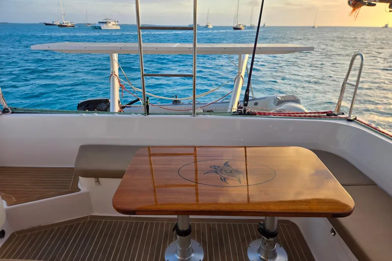 Slide: The Image of Outremer 45 catamaran deck with wooden table, ocean view, and anchored boats, 2016 model. - 21
