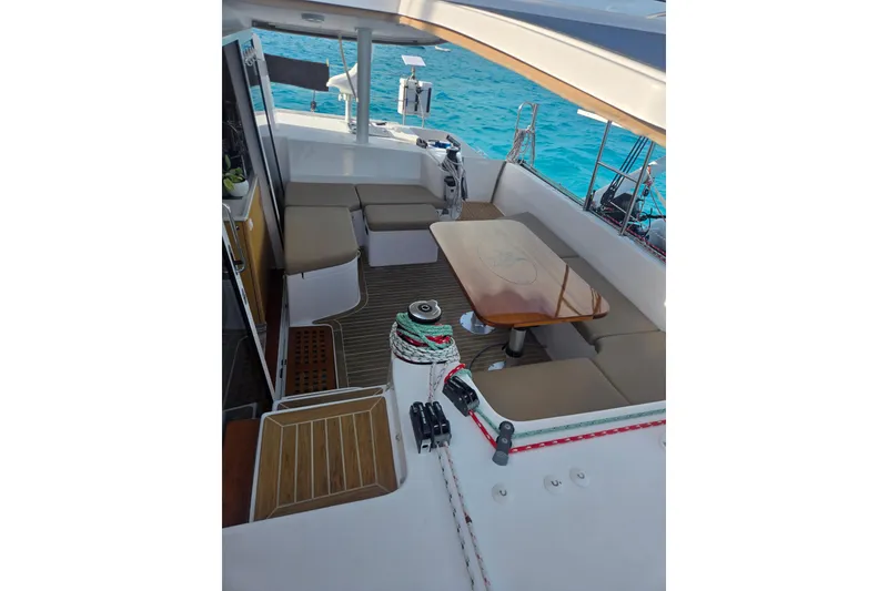 Slide: The Image of Outremer 45 catamaran cockpit with seating and table, 2016 model, on turquoise water. - 25