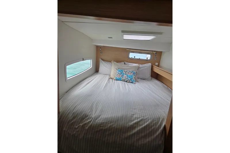 Slide: The Image of Cozy bedroom interior of 2016 Outremer 45 yacht with striped bedding and decorative pillows. - 4