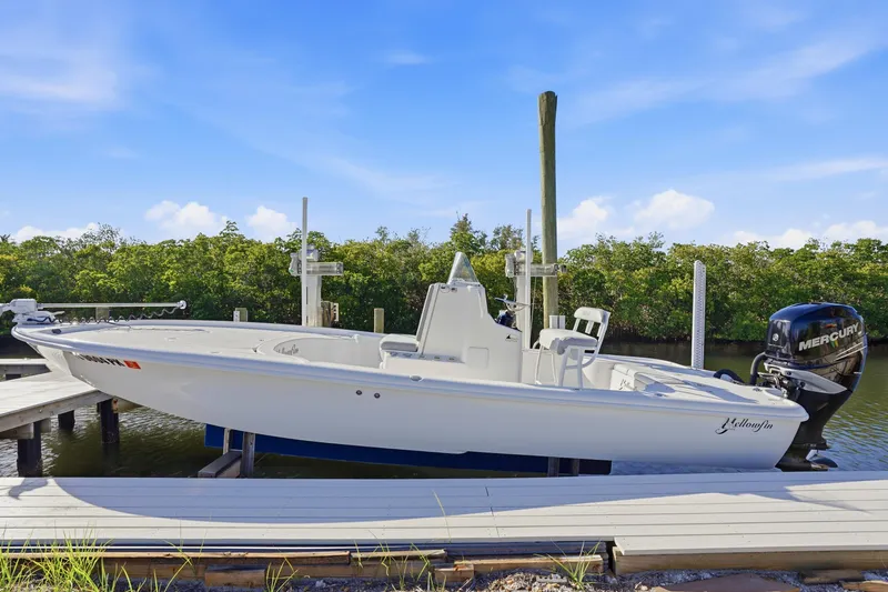 Slide: The Image of 2013 Yellowfin 24 Bay boat docked, showcasing open storage compartments and sleek design. - 19