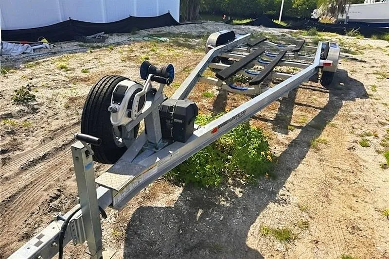 Slide: The Image of Trailer for 2013 Yellowfin 24 Bay boat with dual axles on a dirt surface. - 28