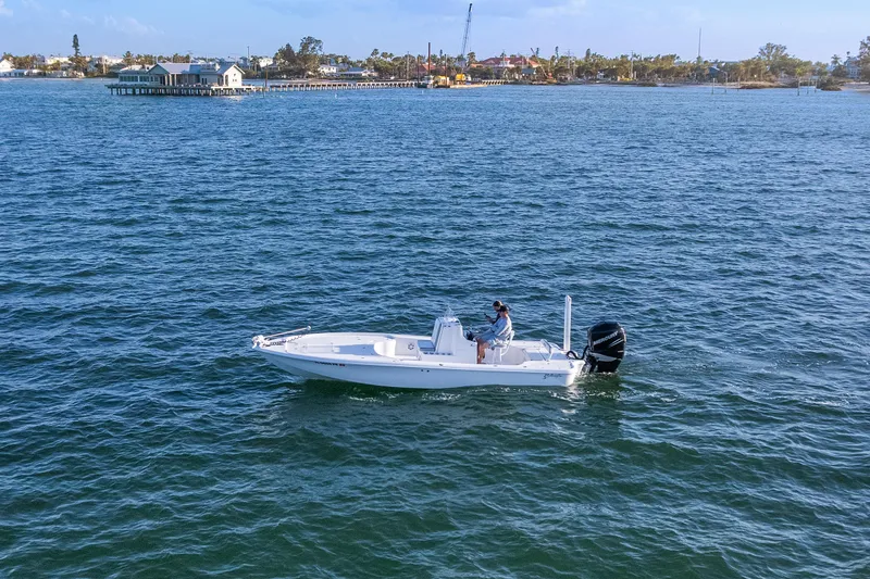Slide: The Image of 2013 Yellowfin 24 Bay boat cruising on open water near a coastal town. - 9