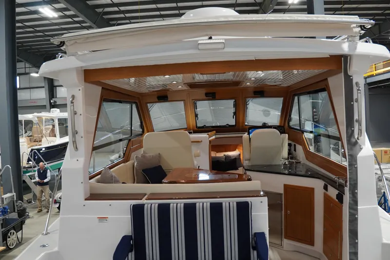 Slide: The Image of 2024 True North 34 boat interior with seating, table, and helm in a showroom. - 21
